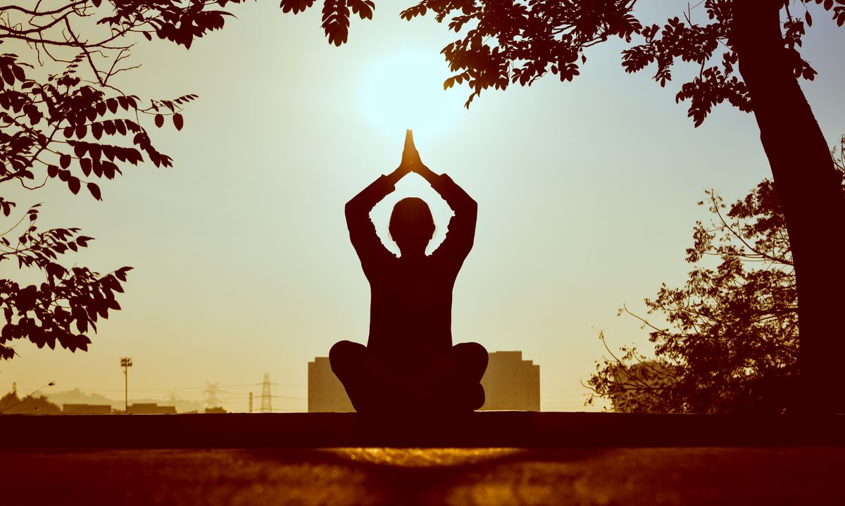 Person meditating outdoors at sunset